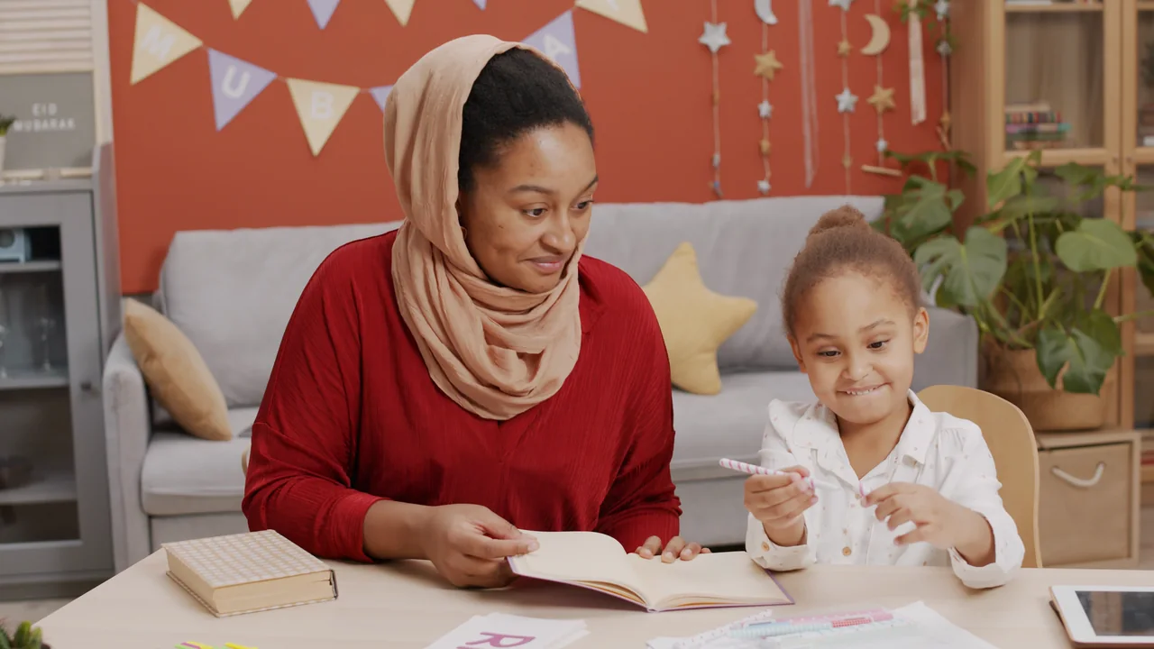 A mother reading and writing with her young daughter at home